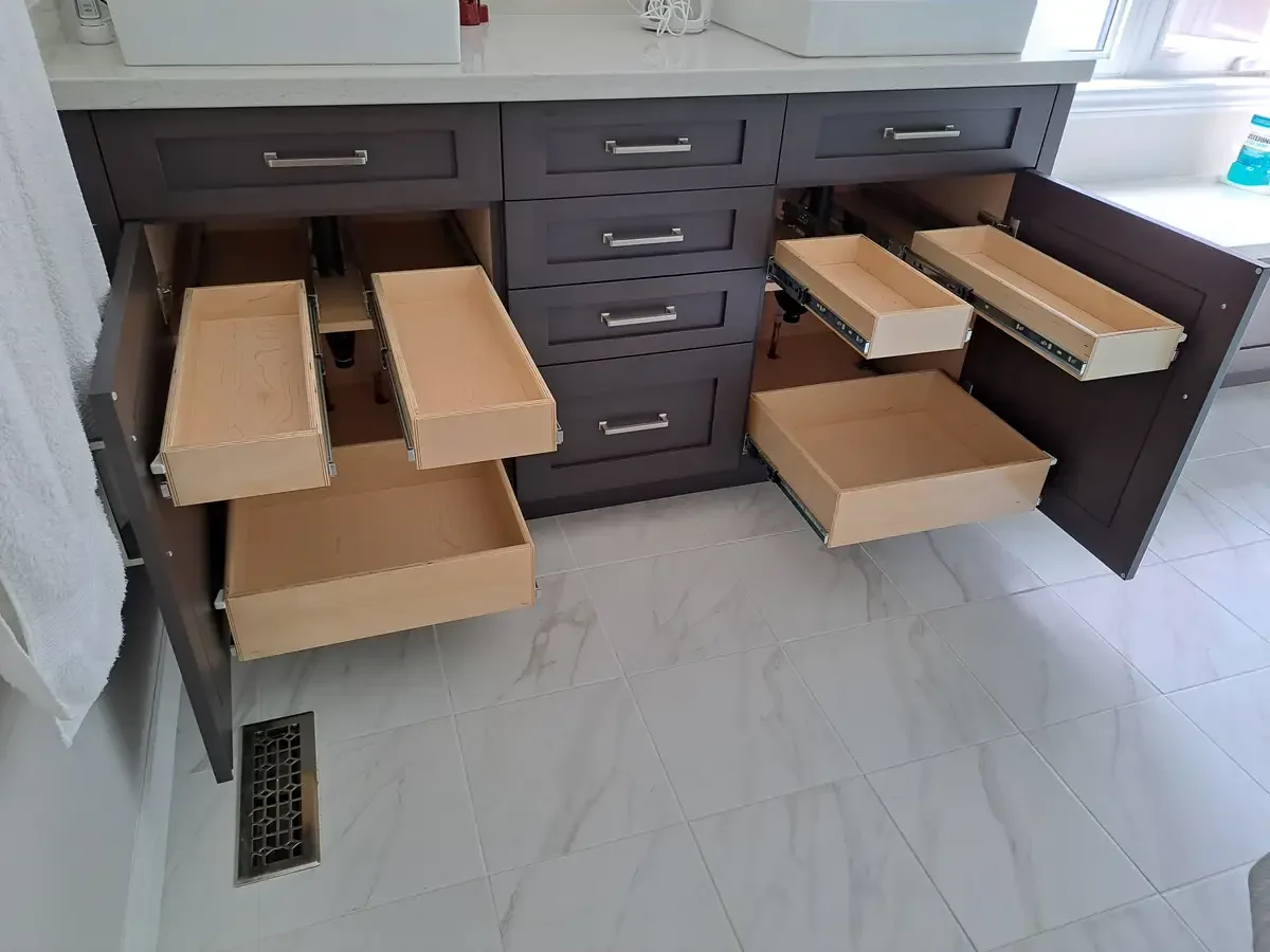 Bathroom vanity fitted with birch pull-out shelves extended over a marble tile floor