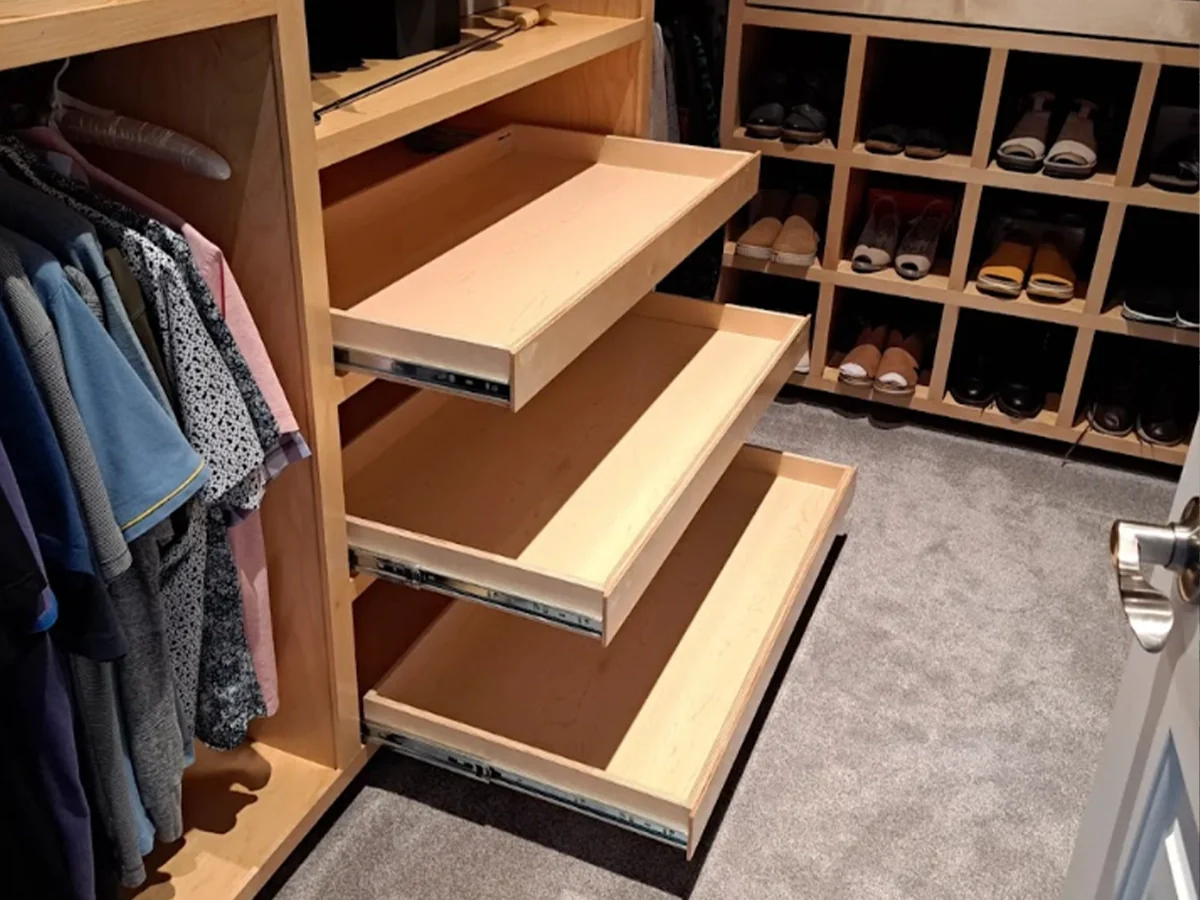 Custom closet with birch pull-out shelves beside hanging clothes and a built-in shoe rack